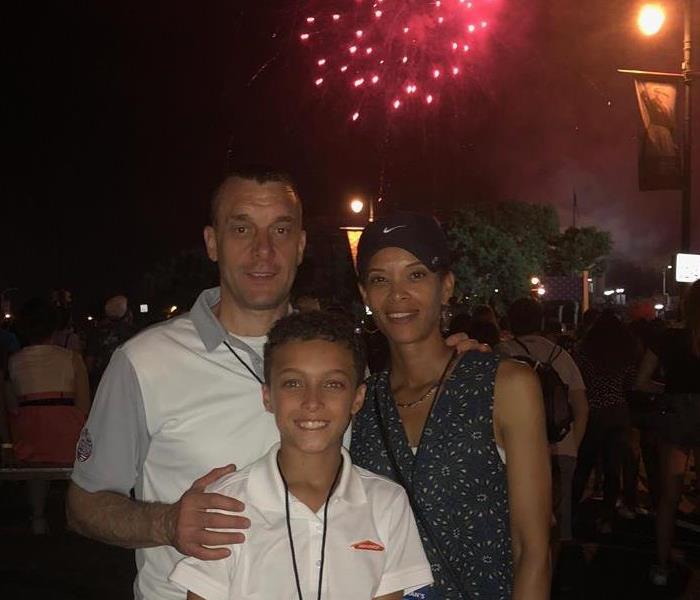 Owner Sean standing with his wife and son, fireworks in the background
