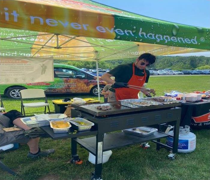 Stephen cooking over a grill with a servpro tent surrounding him